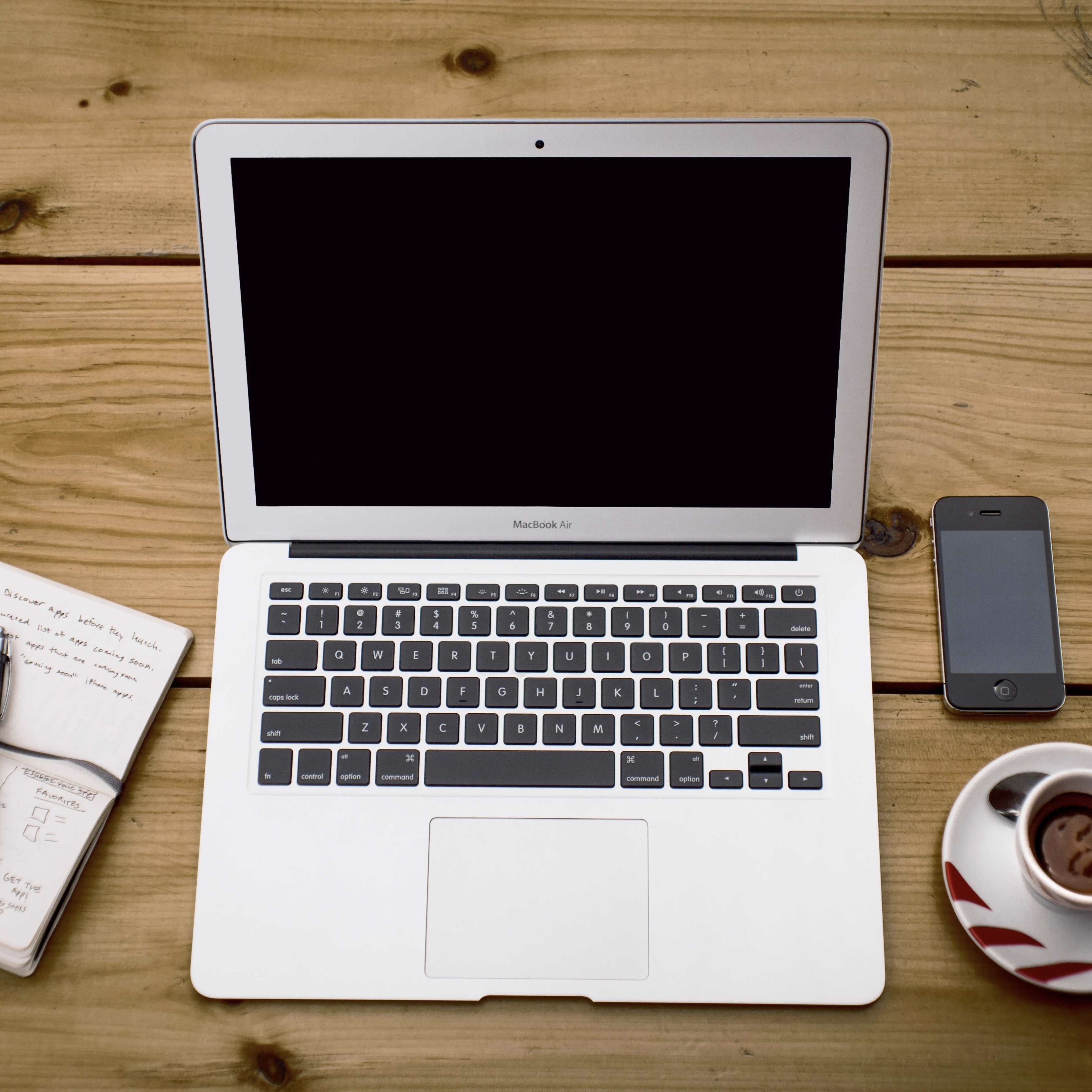 A 1:1 image of the macbook, half a notebook to the left of it, the iPhone and half a cup of coffee on the right